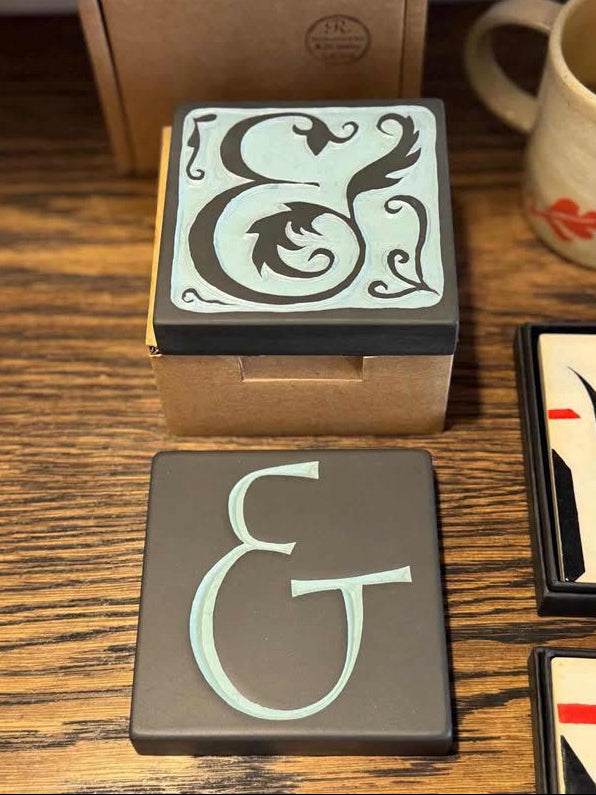 Decorative coasters with ampersand design on a wooden surface