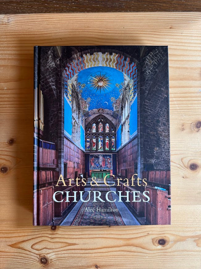 Book titled 'Artés & Crafts Churches' by Alec Hamilton on a wooden surface
