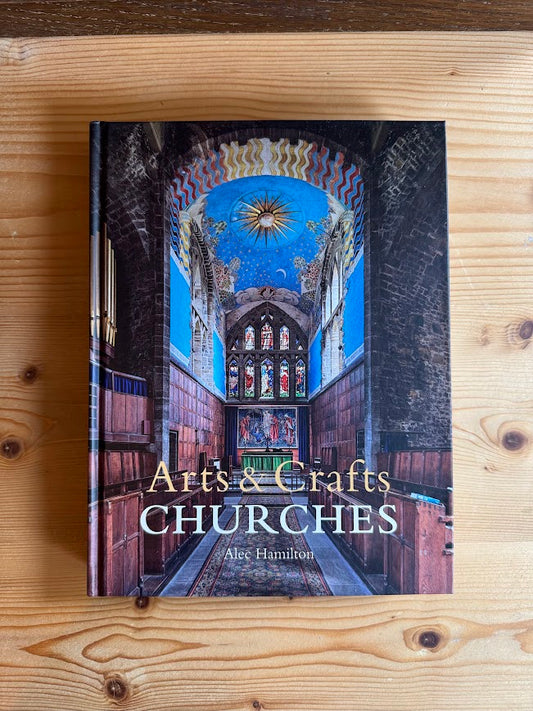 Book titled 'Artés & Crafts Churches' by Alec Hamilton on a wooden surface