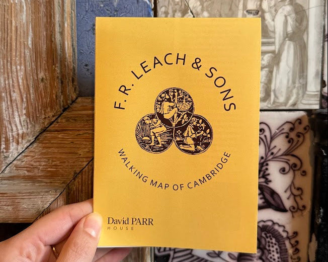 Yellow walking map of Cambridge by F.R. Leach & Sons held against a decorative background.