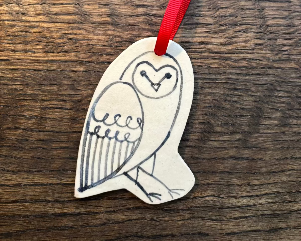 Decorative owl ornament with a red ribbon on a wooden surface