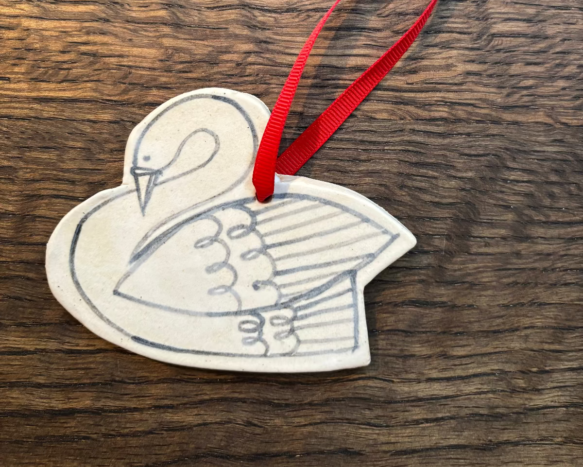 Decorative swan ornament with a red ribbon on a wooden surface