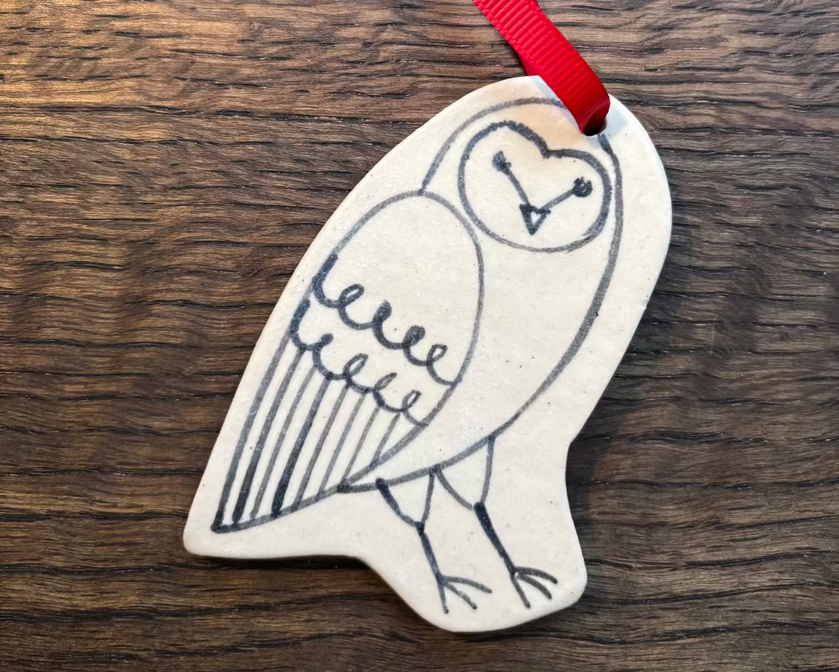 Decorative owl ornament with a red ribbon on a wooden surface