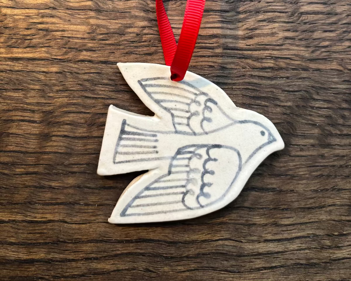 Decorative dove ornament with red ribbon on a wooden surface