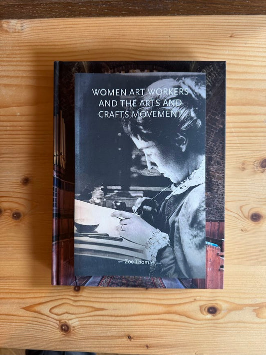 Book titled 'Women Art Workers and the Arts and Crafts Movement' on a wooden surface